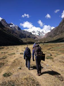 two people walking up a valley to a glacier