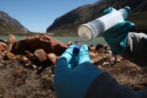 hands using a syringe and filtering water into small bottle