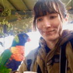 A picture of me looking at a Parakeet perched on my finger.