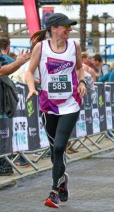 picture of woman (me) wearing running clothes, running and smiling