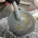 A mortar and pestle with some brown powder in it.
