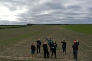 Aerial picture of a group of people standing in a field waving at the camera