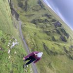 A picture of me in a purple coat and grey hat stood on a ledge in Peak District