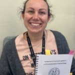 Grace smiling with a printed draft of her thesis
